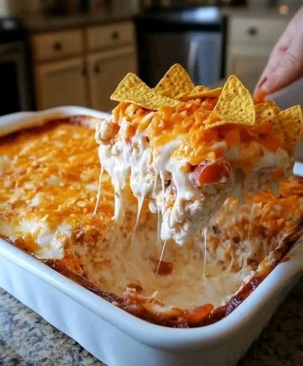 a person scooping some food out of a casserole dish with tortilla chips