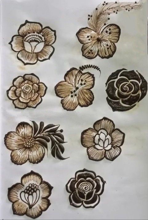 some flowers are drawn on a piece of paper with brown and white ink in it