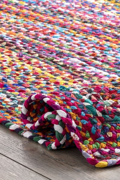 a multicolored rug is laying on top of a wooden floor and it's end rolled up