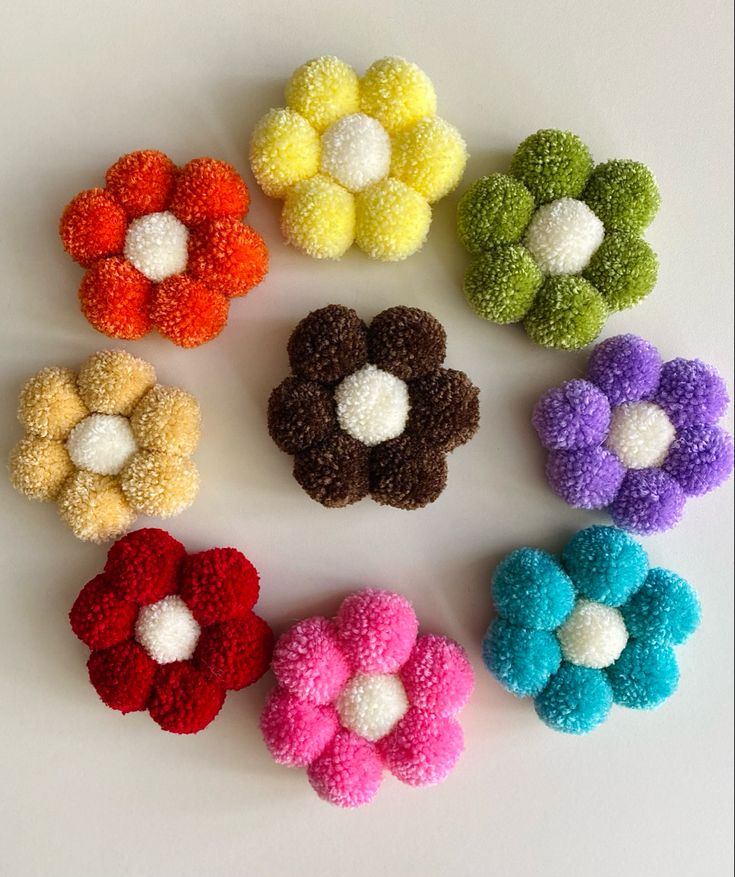 six different colored pom - poms arranged in a circle on a white surface