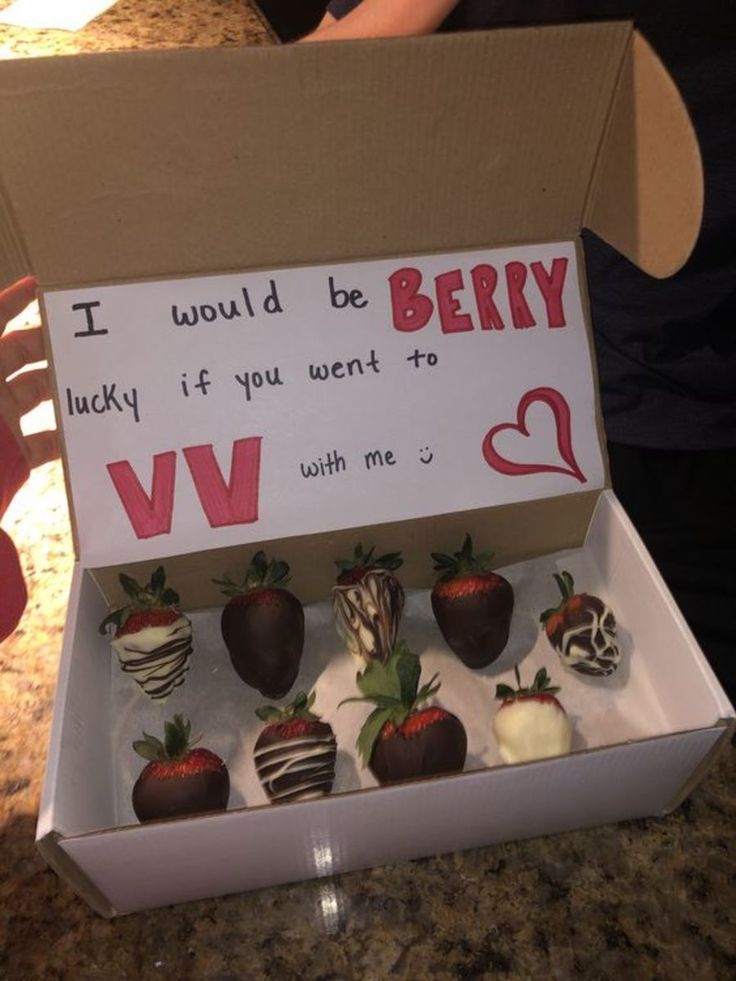 a box filled with chocolate covered strawberries sitting on top of a counter next to a sign