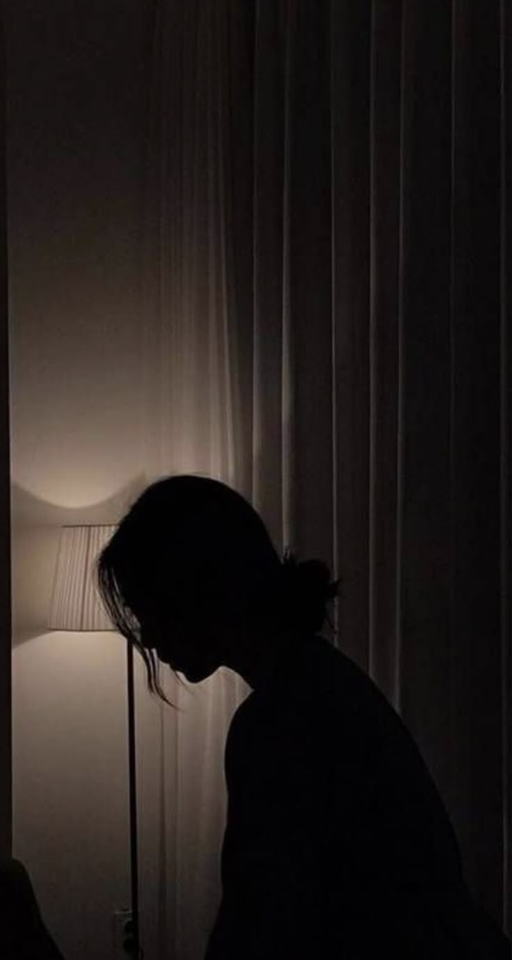 a person standing next to a lamp in a dark room