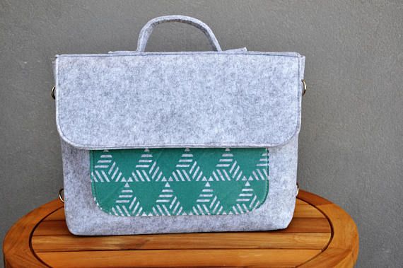 a laptop bag sitting on top of a wooden table next to a gray and white wall