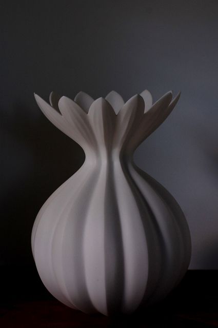 a white vase sitting on top of a wooden table