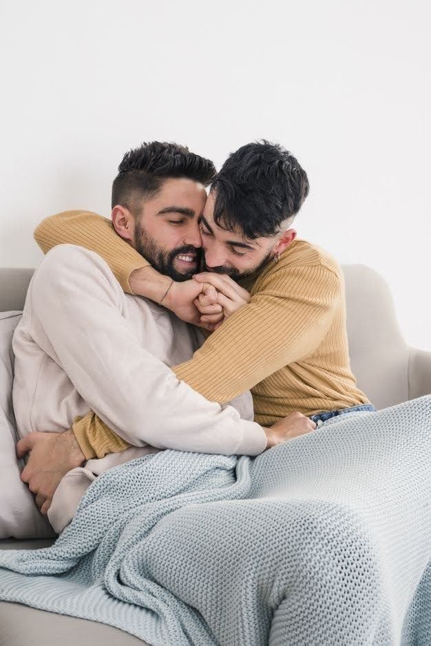 two men hugging each other on a couch