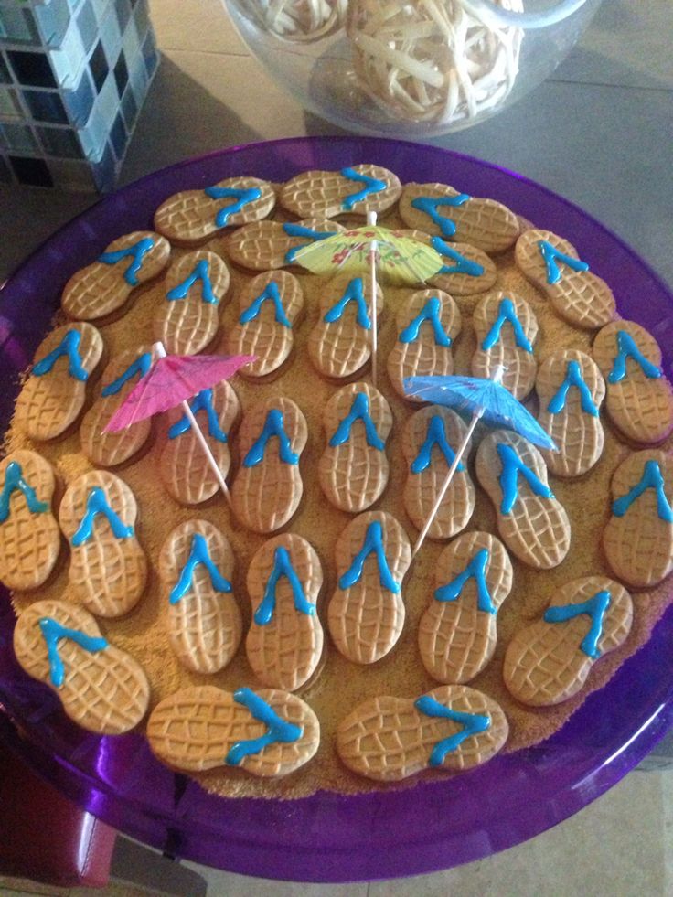 a purple plate topped with cookies covered in blue icing and decorated like umbrellas