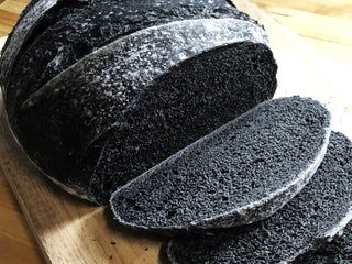 sliced black bread sitting on top of a wooden cutting board