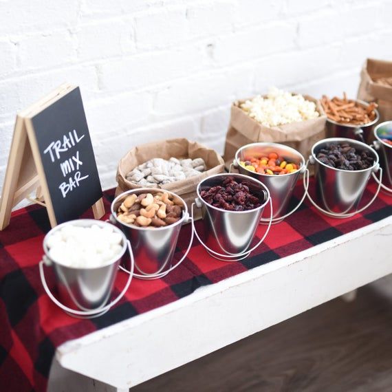 a table topped with metal buckets filled with different types of food next to a chalkboard sign