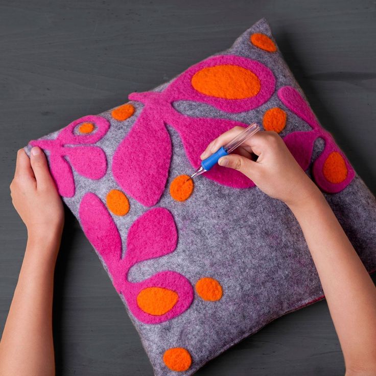 a person is using a marker to draw on a decorative pillow that has been made with felt