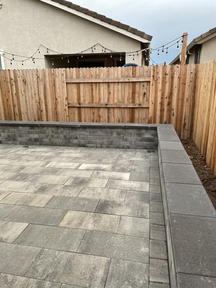 an empty backyard with concrete pavers and wooden fence