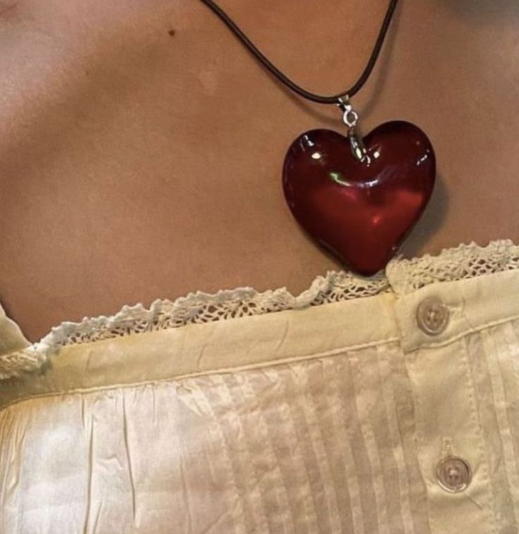 a woman wearing a red heart shaped necklace on her chest and white shorts with lace