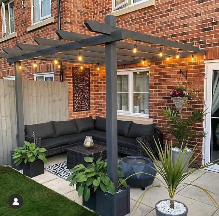 an outdoor living area with couches and potted plants in front of a brick building