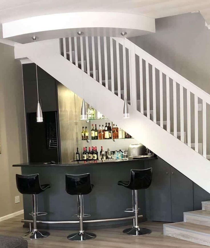 a bar with three stools under the stairs