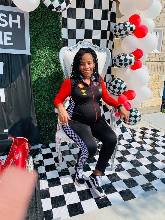 a woman sitting on a chair in front of a checkerboard backdrop and balloons