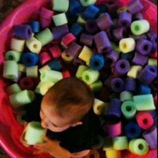 a baby in a bowl filled with lots of beads