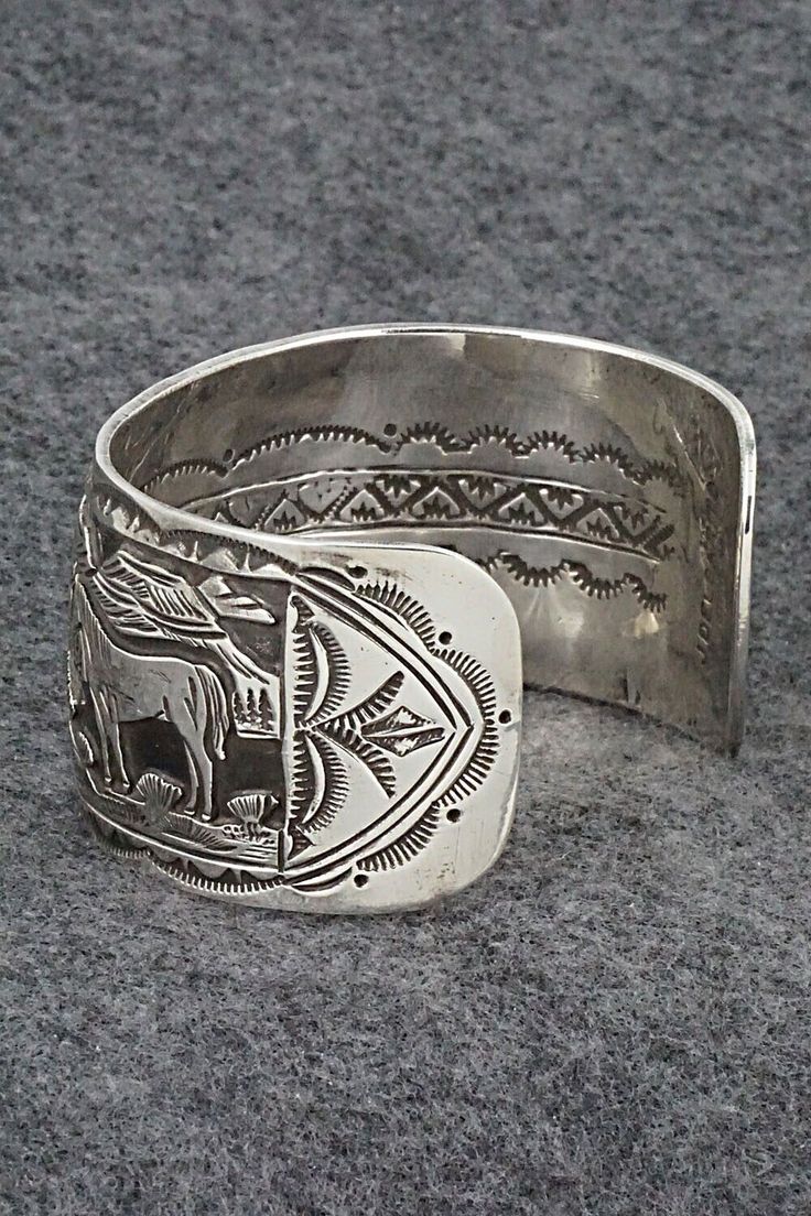 This sterling silver bracelet featuring horses grazing in a Southwestern landscape was made by Navajo silversmith Jeremy Delgarito. The back is signed J Delgarito and stamped sterling.Size: 5 3/8" (will fit up to a 6 3/4" wrist)Gap: 1 3/8"Width: 1 1/4"Free shipping on all orders! We ship with USPS and always include tracking. All orders ship within a day of payment.Returns are accepted up to 30 days after you receive your order. Just send us a message. Our shop offers cash back or store credit. Handcrafted Silver Bracelets As Gift, Hand Tooled Silver Bracelet As A Gift, Hand Tooled Silver Bracelets As A Gift, Silver Hand Tooled Bracelet For Gift, Hand Tooled Silver Bracelet For Gift, Engraved Sterling Silver Bracelet Gift, Bohemian Sterling Silver Engraved Bracelet, Western Style Silver Jewelry For Collectors, Western Style Silver Cuff Bracelet As A Gift