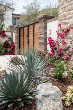 an outdoor area with flowers and plants in the foreground, along with a stone wall