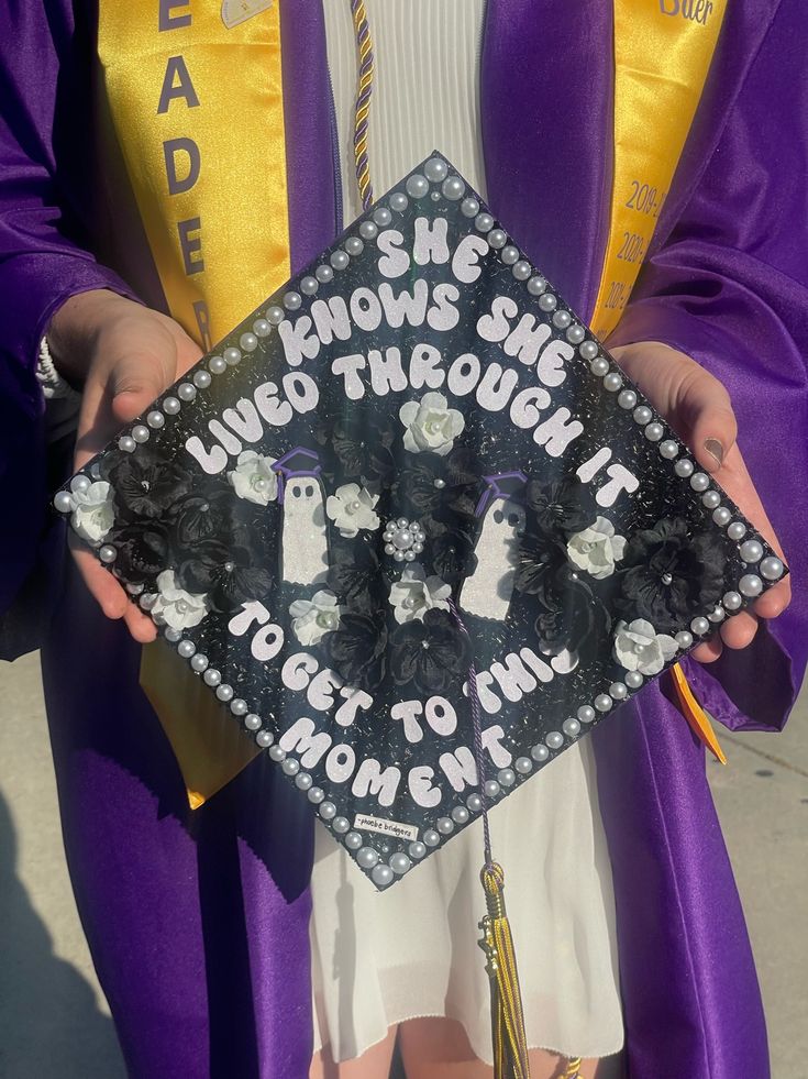 a person in a purple graduation gown holding a sign that says she knows she was through it to get to her mom