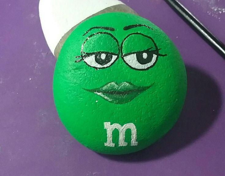 a close up of a green rock with a face painted on it and a straw sticking out of the top