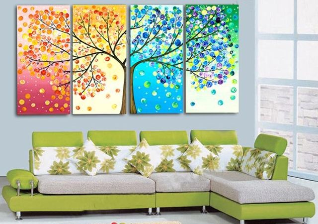 three colorful paintings are hanging on the wall in a living room with green couches