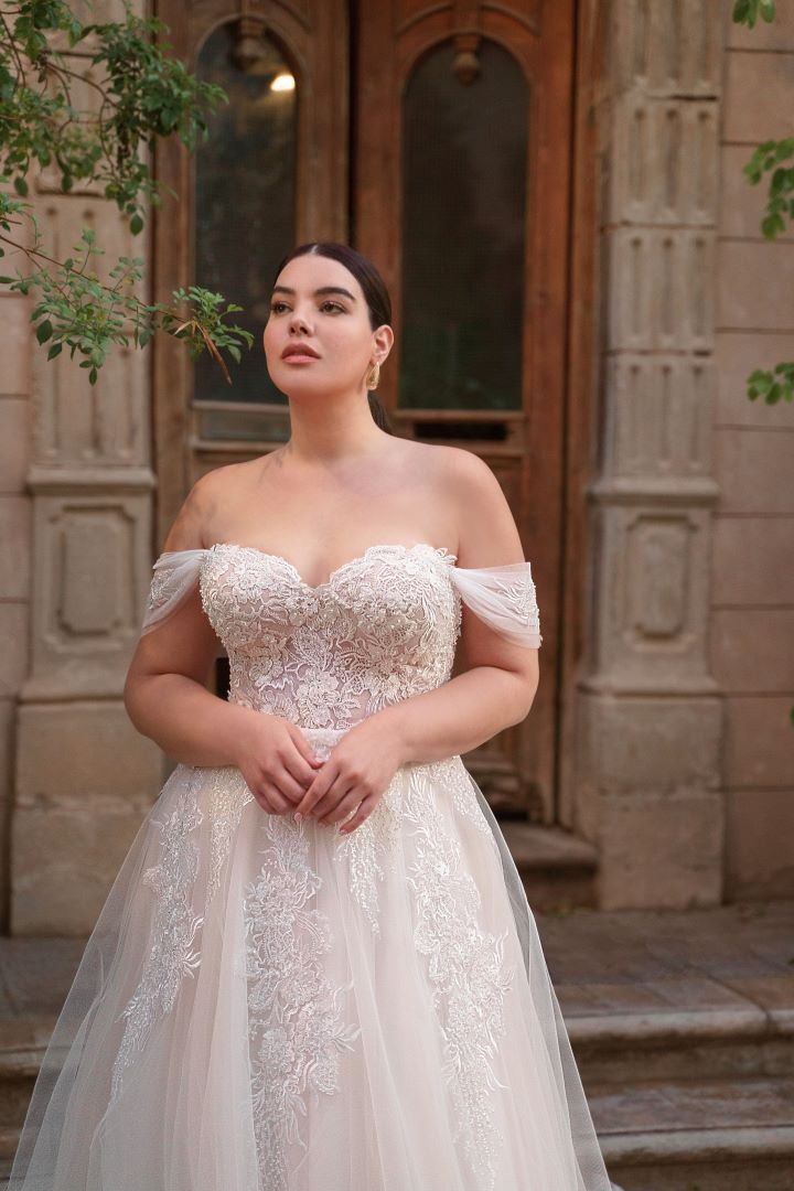 a woman wearing a wedding dress standing in front of a building with her hands on her hips