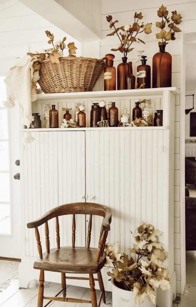 a wooden chair sitting in front of a shelf filled with vases and bottles on top of it