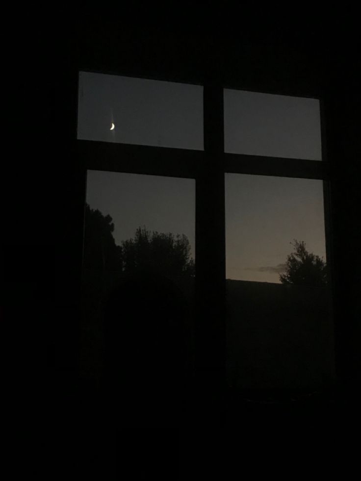 the moon is seen through two windows at night