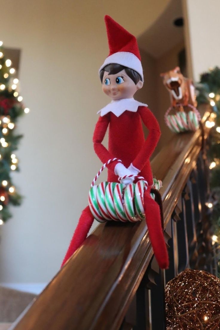 an elf sitting on top of a banister next to christmas decorations