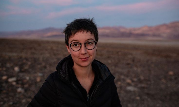 a woman wearing glasses standing in the desert