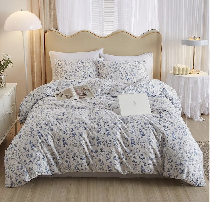 a bed with blue and white flowers on it in a bedroom next to a window