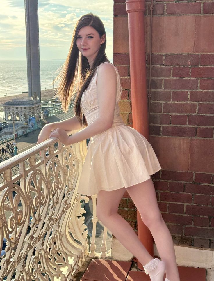 a woman in a short dress leaning on a railing