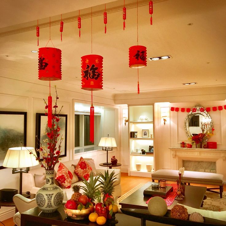 a living room filled with lots of furniture and red lanterns hanging from the ceiling above