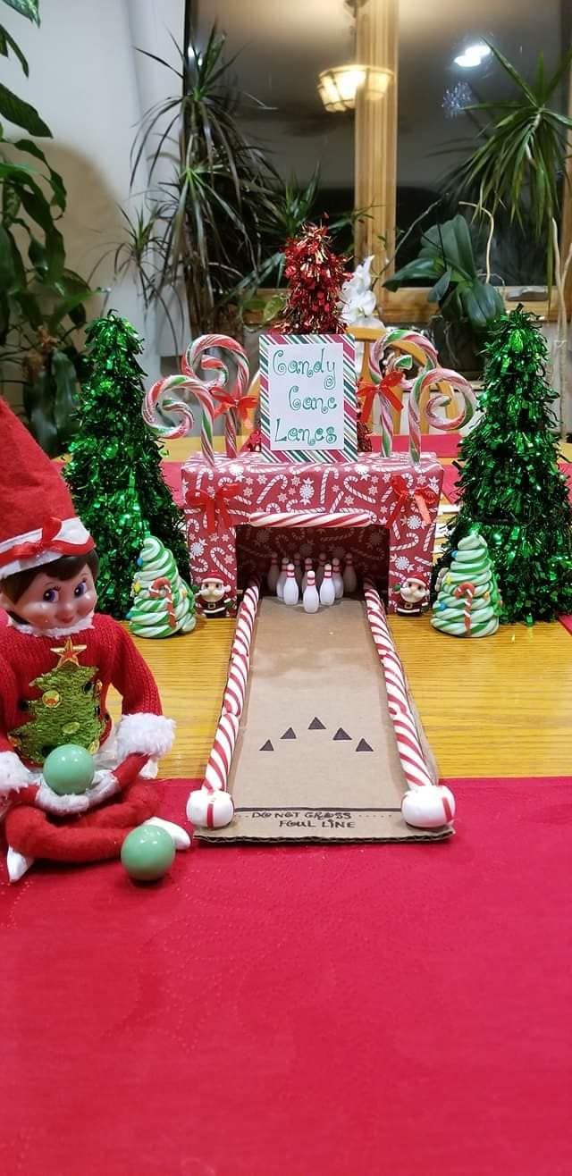 an elf is sitting on the floor in front of a christmas display with candy canes