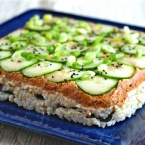 a blue plate topped with rice and cucumber slices