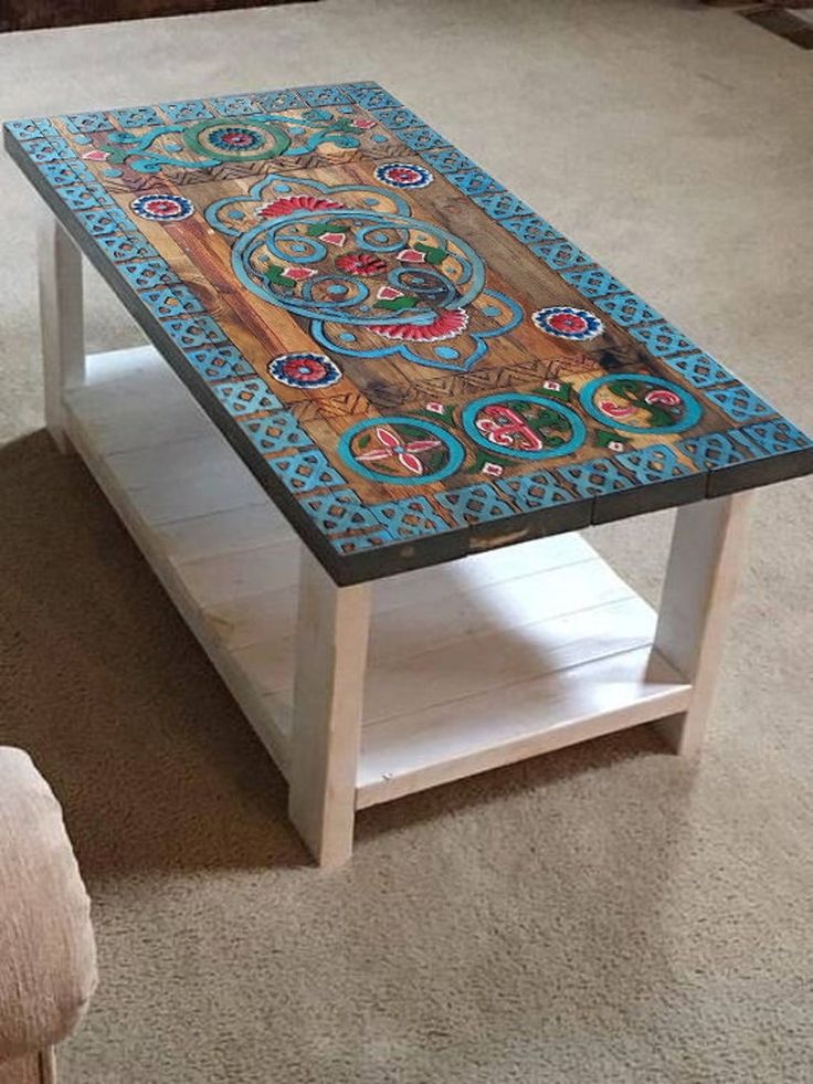 a coffee table with an intricately painted design on the top and bottom, sitting in a living room