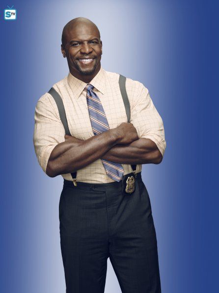 a man with his arms crossed wearing a shirt and tie, standing in front of a blue background