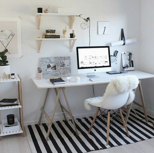 a white desk with a computer on top of it next to a black and white rug