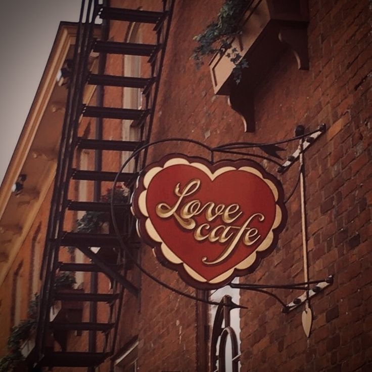 a sign on the side of a building that says love cafe with a red heart