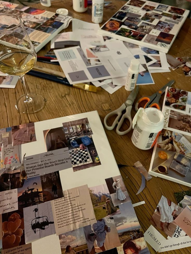 a wooden table topped with lots of pictures and wine glasses filled with liquid next to scissors