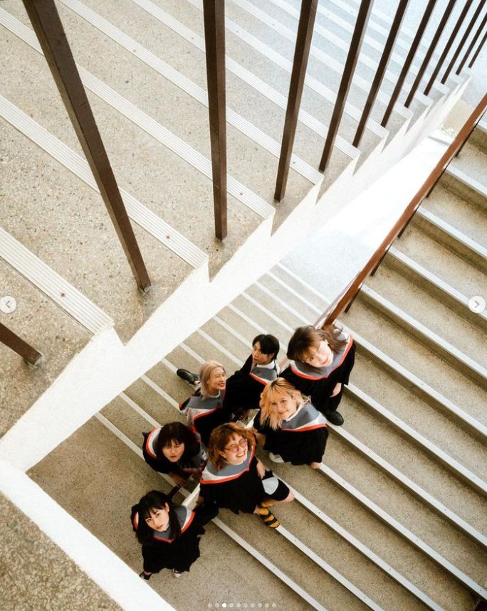 a group of young people standing on top of a stair case next to each other