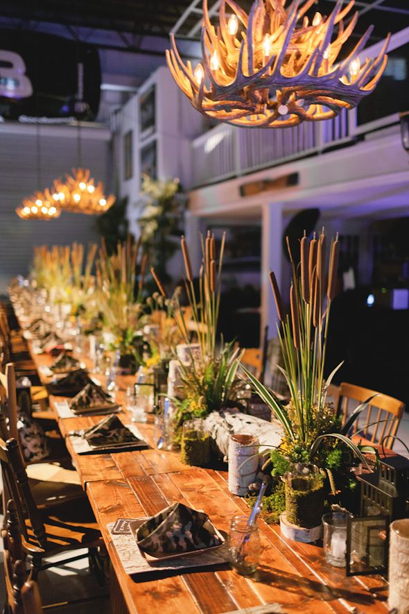 a long wooden table topped with lots of potted plants next to a chandelier