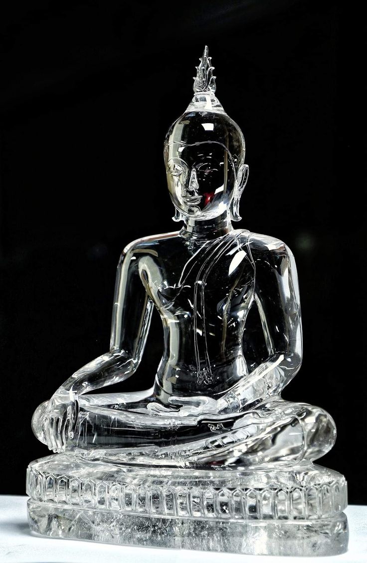 a glass buddha statue sitting on top of a table