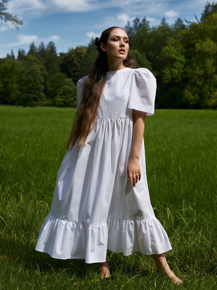 Slightly oversized and airy dress with statement shaped cap sleeves and a ruffle midi hem. Tied with a bow at the back. White soft cotton poplin Fabric: 100% cotton The model is wearing size S Designed and made in Prague This item depends on the bust size only (measure across your bust and base on bust measurement) Cotton Midi Dress With Ruffle Sleeves, Spring Voluminous Short Sleeve Puff Dress, Feminine Cotton Midi Dress With Ruffle Hem, Daywear Dresses With Ruffles And Voluminous Skirt, Cotton Midi Dress With Gathered Sleeves For Garden Party, White Cotton Dress With Voluminous Skirt, Feminine Cotton Midi Dress With Gathered Sleeves, Cotton Midi Dress With Ruffles And Short Sleeves, Voluminous Midi Dress With Puff Sleeves And Ruffles