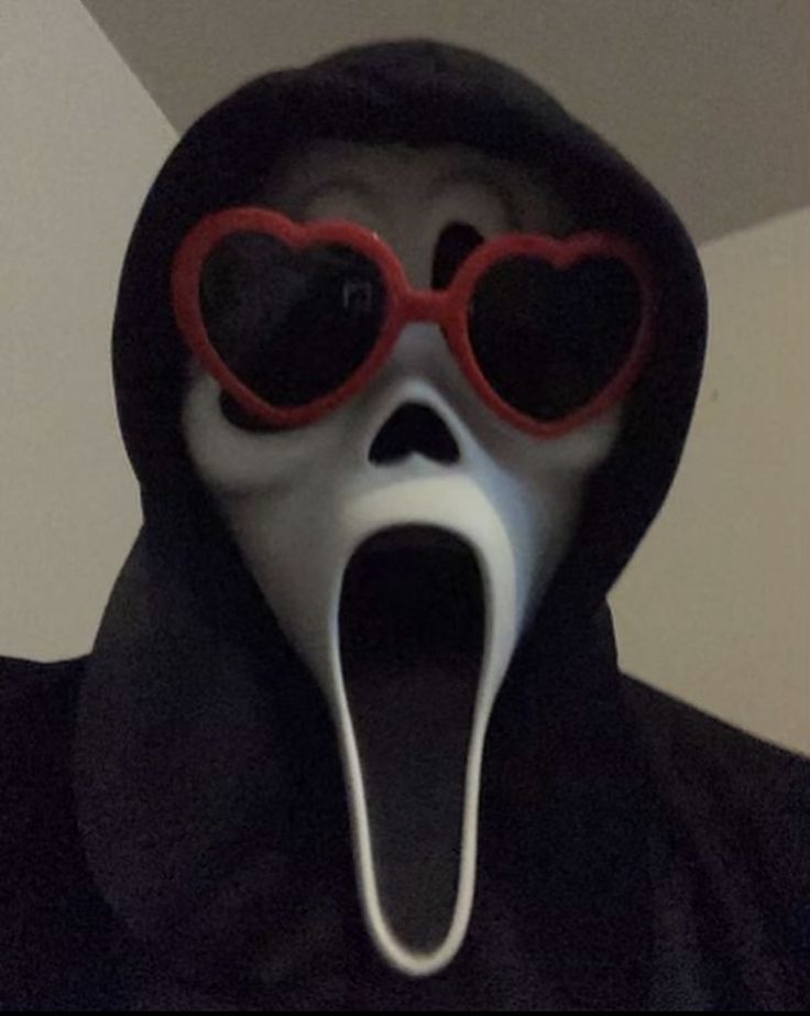 a person wearing a mask with heart shaped glasses on their face and tongue sticking out