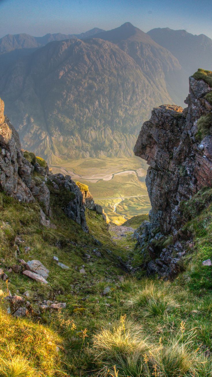 an open area in the mountains with grass and rocks