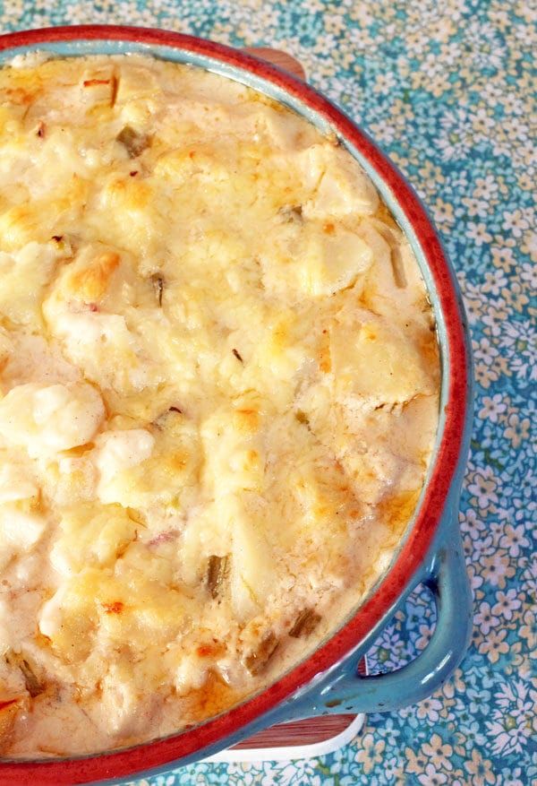 a casserole dish with meat and cheese in it on a blue floral tablecloth