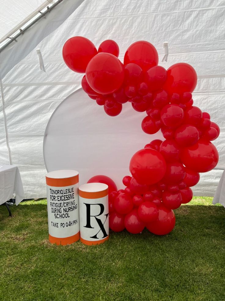 red balloons are on display in front of a white tent