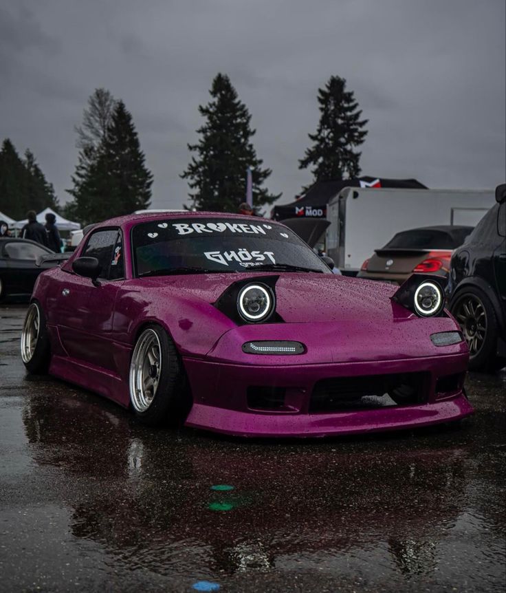 a purple car parked on top of a wet parking lot