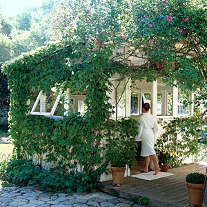 a woman is standing in front of a house with ivy growing on the side of it