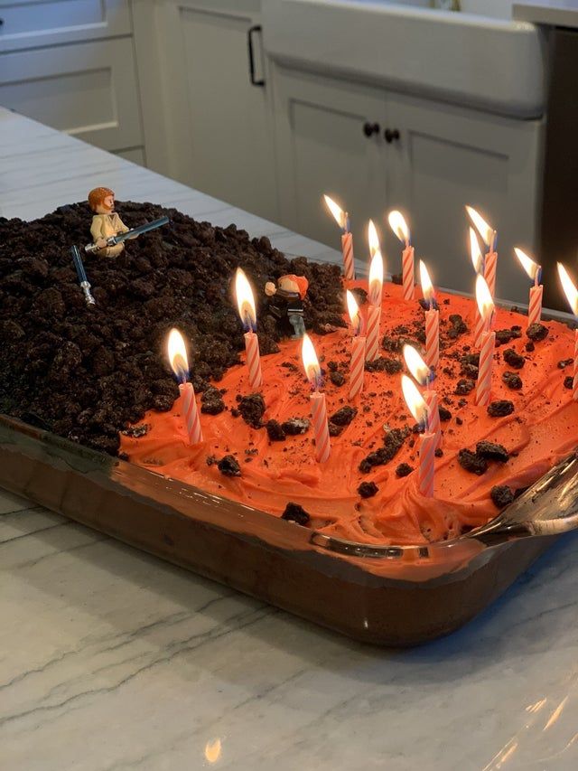 a birthday cake with orange frosting and lit candles